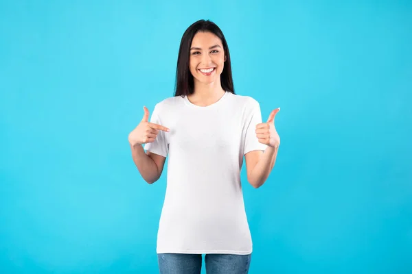 Mujer joven y feliz señalando con los dedos a la camiseta — Foto de Stock