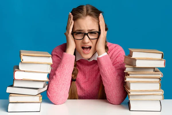 Menina gritando e segurando cabeça, perto de um monte de livros — Fotografia de Stock