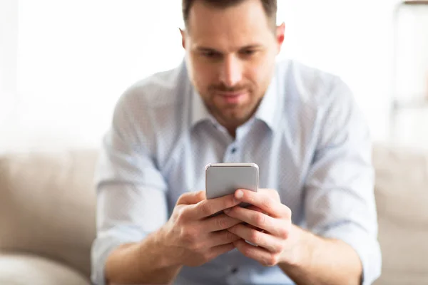 Handsome adult man using smartphone at home — Stock Photo, Image