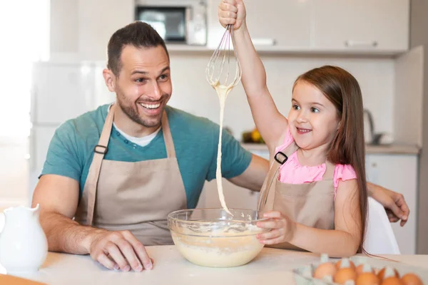 Father And Daughter Making Dough Having Fun In Kitchen Indoors