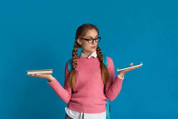 Menina adolescente escolhe entre livro e tablet — Fotografia de Stock