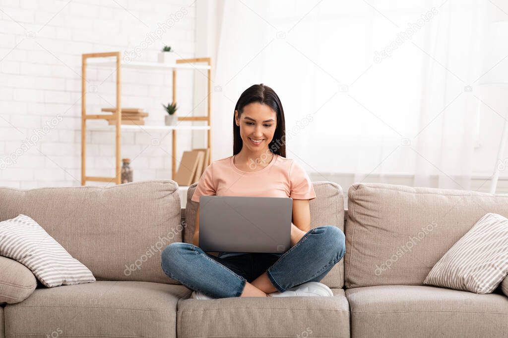 Woman using laptop phone sitting on sofa, free space