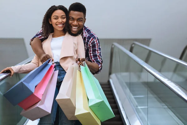 Verkoopseizoen. Vreugdevol Afrikaans paar met veel boodschappentassen in handen — Stockfoto