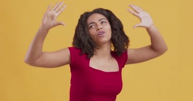 Zenci kız dans ediyor, turuncu arka planda dinamik müzikten hoşlanıyor.