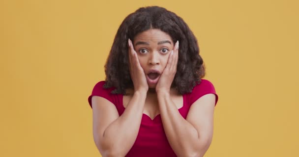 Schockierte schwarze Frau berührt Wangen und empfindet Erstaunen — Stockvideo