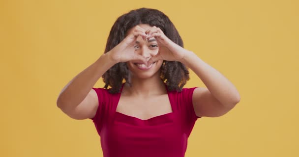 Mujer negra feliz mirando a través del corazón hecho — Vídeos de Stock