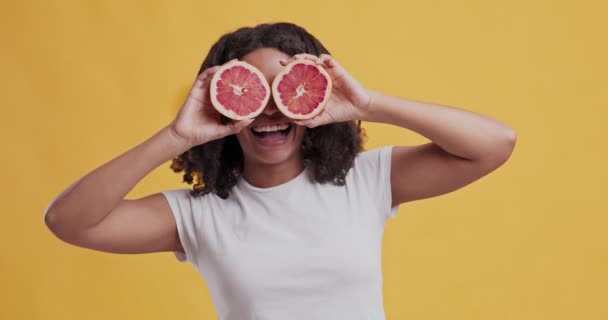 Vidám afro-amerikai nő kezében grapefruit közel szemek — Stock videók