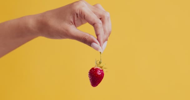 Red ripe strawberry in female hand, orange background — Stock Video