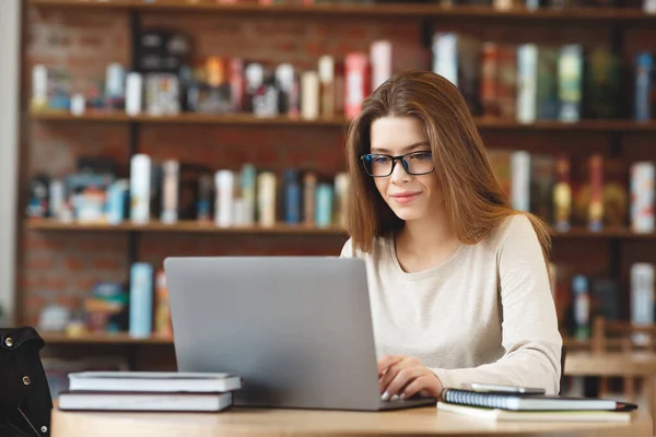 Estudante encantadora usando net-book no laptop enquanto sentado no café — Fotografia de Stock