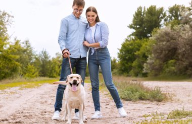 Tatlı bir çift ve Golden Retriever kırsalda yürüyor.