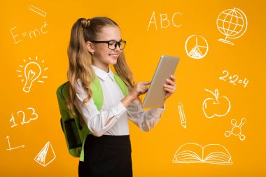 Eğitim ve aletler. Gözlüklü, tablet kullanan, eğitim sembolleri etrafında sevimli bir kız.