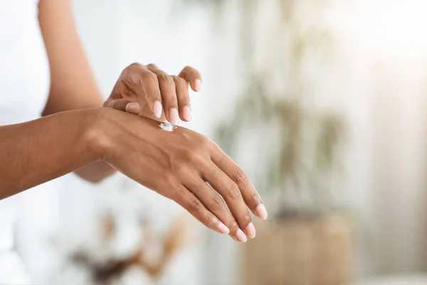 Hautfeuchtigkeitscreme. Afro-Frau trägt reichhaltige Handcreme auf und macht tägliche Schönheitsbehandlungen — Stockfoto