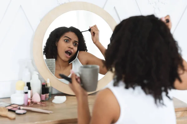 Mujer negra aplicando maquillaje a toda prisa, bebiendo café y hablando por celular —  Fotos de Stock
