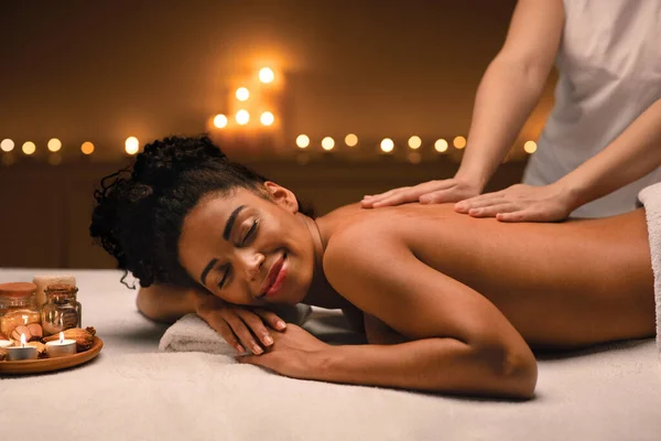 Mulher afro-americana desfrutando de atmosfera romântica durante a massagem corporal — Fotografia de Stock