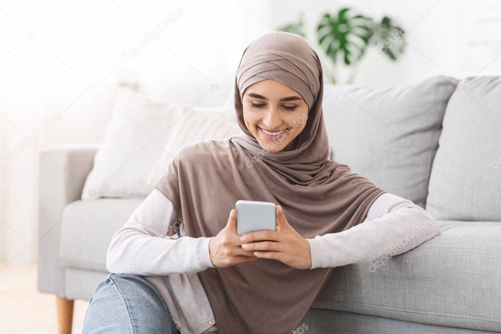 Pleasant Message. Smiling arabic woman reading sms on smartphone at home