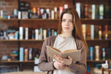 Hayalperest kız kafede tek başına oturmuş kitap okuyor.