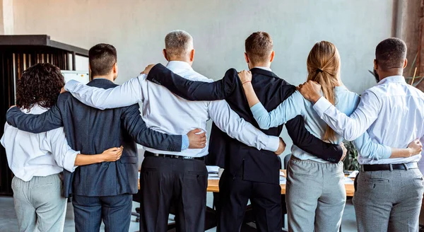 Equipe de negócios abraçando de volta à câmera no escritório, Panorama — Fotografia de Stock