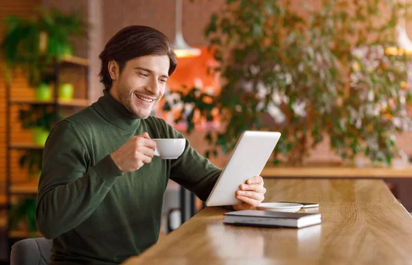 Feliz joven empresario leyendo noticias mientras bebe café en la cafetería — Foto de Stock