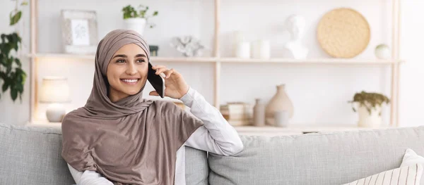 Panggilan yang menyenangkan. Modern Muslim Girl In Hijab Talking On Cellphone At Home — Stok Foto