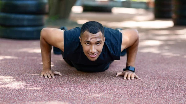 Silný africký Anerican sportovec dělá push up cvičení po jogging v parku v dopoledních hodinách — Stock fotografie