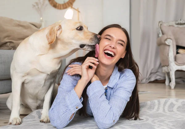 Young smiling woman with dog lying on floor — Stock Photo, Image