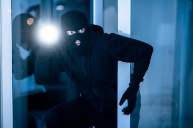 Thief breaking into apartment to steal, using torch clipart