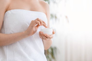 Evde duştan sonra krem kullanan tanınmayan bir kadın.