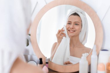 Güzel kız evde duş aldıktan sonra yüzünü kurutuyor.