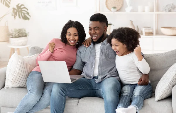 Online loterij. Opgewonden Afro-Amerikaanse familie van drie vieren winnen met laptop — Stockfoto