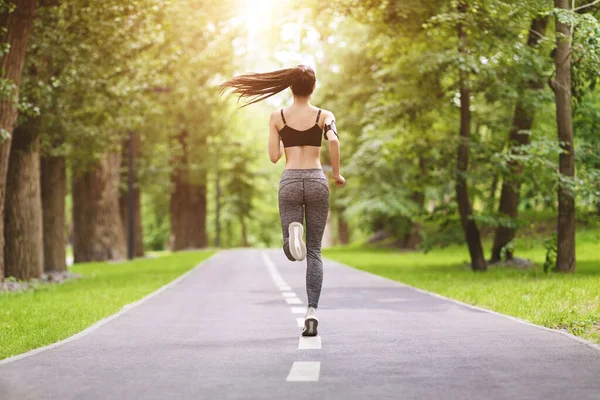 Спортивная мотивация. Вид сзади на спортивную девушку, бегающую по дорожке в парке — стоковое фото