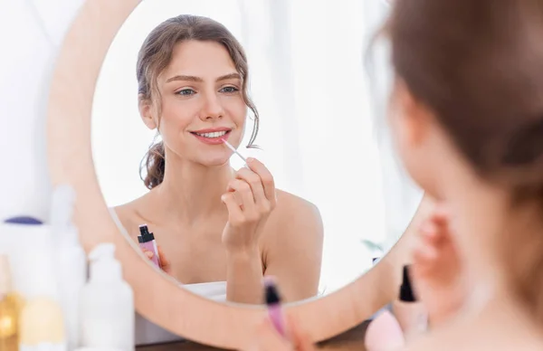 Beautiful lady applying lipstick in front of mirror — Stock Photo, Image