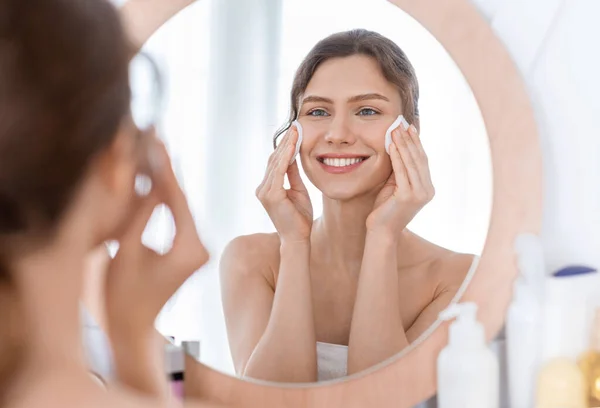 Junge fröhliche Frau reinigt ihr Gesicht mit Wattepads — Stockfoto