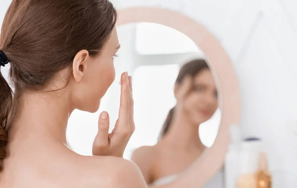Vista posterior de la mujer joven mirando el espejo — Foto de Stock
