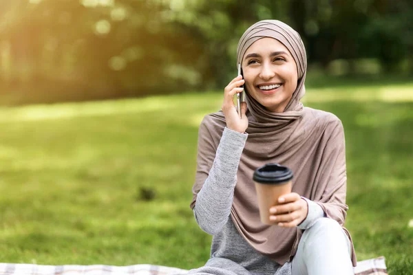 Chica musulmana feliz hablando por teléfono y tomando café —  Fotos de Stock