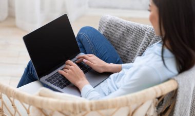 Evde boş siyah ekranlı dizüstü bilgisayarda çalışan bir kadın