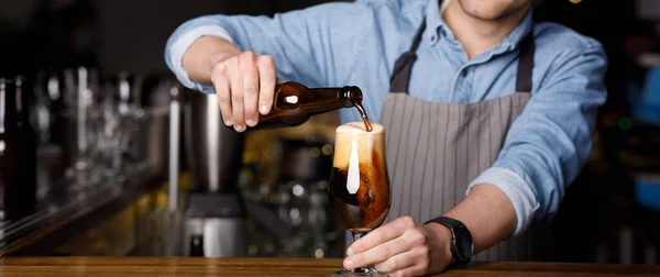 Ordem do cliente no pub. Barman derrama cerveja escura em vidro no bar — Fotografia de Stock