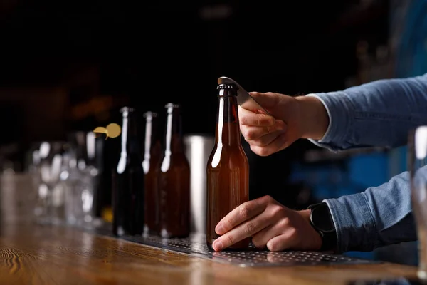 Servicio de atención al cliente en pub. Barman manos botella abierta de cerveza en el bar —  Fotos de Stock