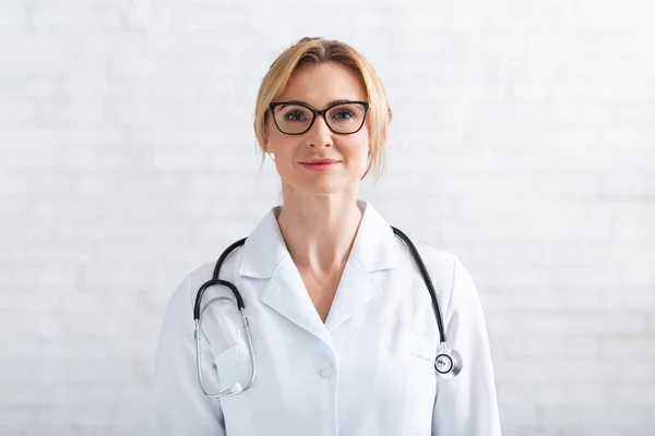 Video call with patient. Woman doctor in white coat watching at camera — Stock Photo, Image