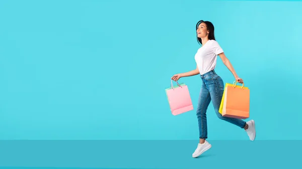 Mujer muy alegre corriendo con bolsas de compras en el estudio —  Fotos de Stock