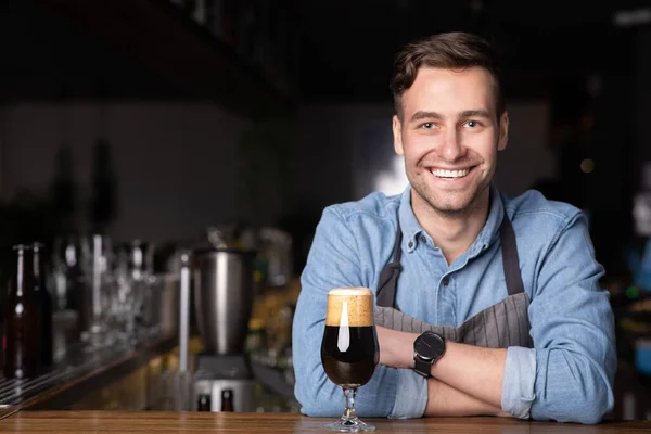 Barman sorridente moderno em avental com braços cruzados no interior do bar — Fotografia de Stock