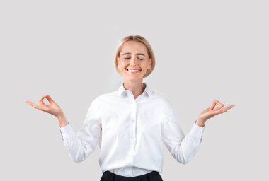 İş yerinde sakin ol. Huzurlu, olgun iş kadını, hafif arka plan üzerinde meditasyon yapıyor.