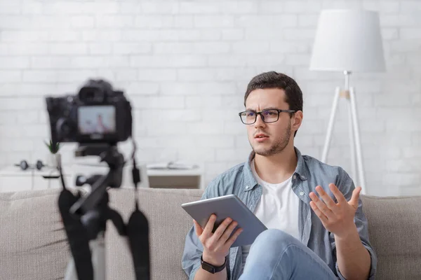 Blogger de medios sociales disparando vlog. Hombre nerd serio en gafas con la tableta en las manos — Foto de Stock