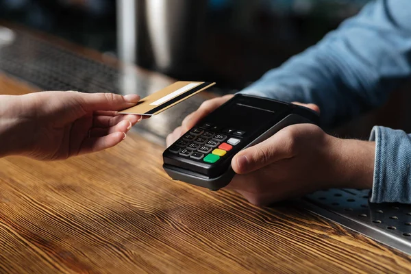 Pagamento contactless moderno da conta no pub. Mão do cliente detém cartão de crédito, bartender segurando terminal — Fotografia de Stock