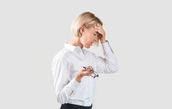 Przepracowany przedsiębiorca cierpiący na migrenę, zmęczenie lub mający problem na lekkim tle — Zdjęcie stockowe