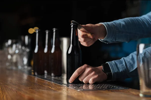 Bezoek aan de pub. Barman opent fles bier in het interieur — Stockfoto