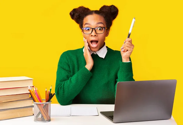 Shocked black teenage raising pensil doing hometask — Stock Photo, Image