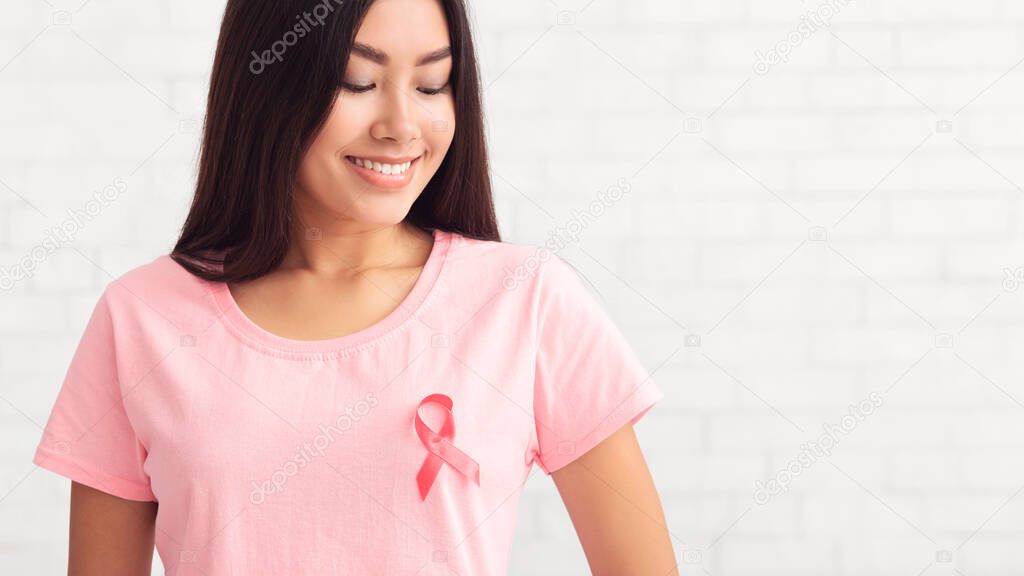 Asian Woman Wearing T-Shirt With Cancer Ribbon Over White Background