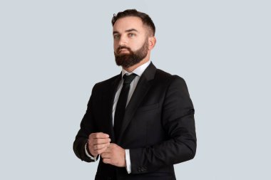 Gri arka planda resmi takım elbiseli ve kravatlı zarif bir iş adamı.
