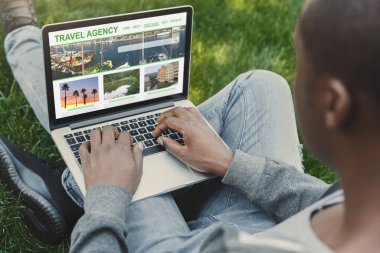 Seyahat acentesi web sitesi. Siyah Adam Laptop 'ı Açık havada kullanıyor, Yeni Yolculuk İstikametini Kaydediliyor