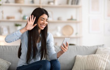 Görüntülü arama. Asyalı kız akıllı telefon kamerasına el sallıyor, arkadaşlarıyla konuşuyor.
